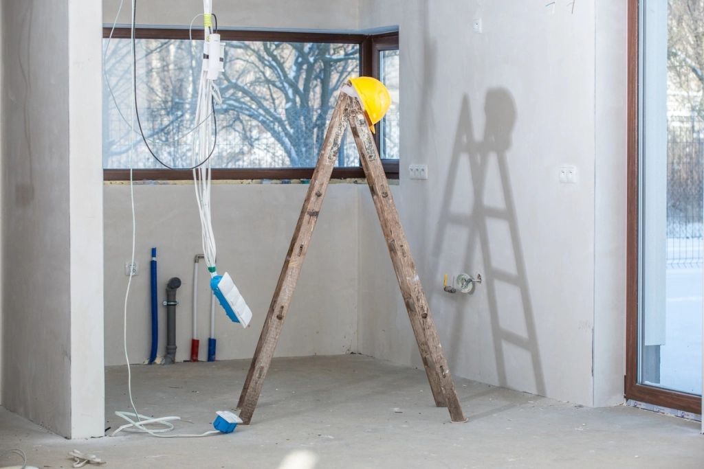 Travaux de rénovation intérieure avec échelle et câbles électriques, illustrant l'aménagement et l'installation électrique.